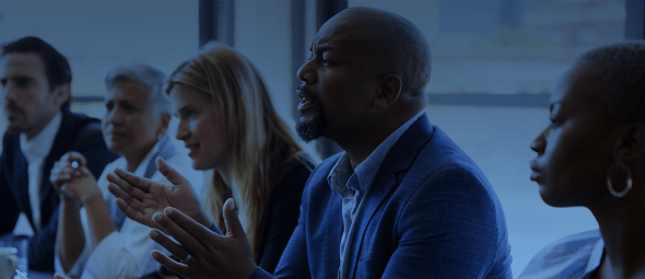 Manger talking while sitting with coworkers at a boardroom table